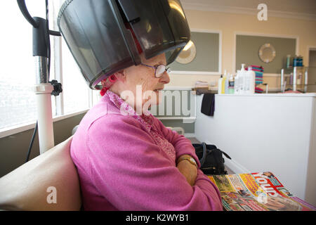 Altersrentner in ihr Haar in einer Haube Haartrockner Lockenstäbe bei einem Damen Friseur, England tragen getrocknet, Vereinigtes Königreich Stockfoto