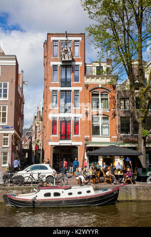 Holland, Norden, Amsterdam, Boot günstig außerhalb typischer gable Gebäude mit drei Statuen auf dem Balkon. Stockfoto