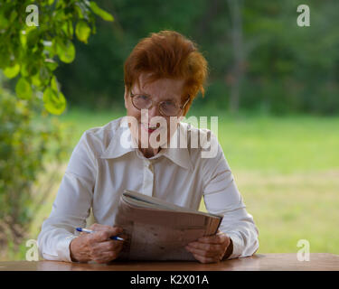 Portrait of a Business woman in einem Alter, das Lesen einer Zeitung. Alter 80 Jahre. Stockfoto
