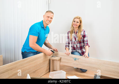 Porträt eines jungen Paares Montage Holzmöbeln im neuen Haus Stockfoto