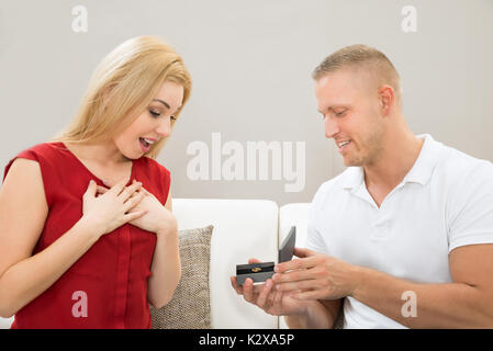Junger Mann, der Ring zu schönen Frau zu Hause Stockfoto