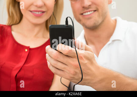 Junges Paar zusammen Musik hören mit Handy Stockfoto