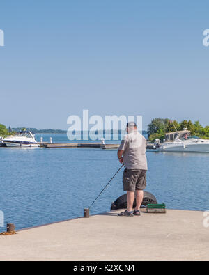 Einsame Mann angeln von der Seebrücke Couchiching Park in Orillia Ontario Kanada an einem schönen Sommertag. Stockfoto