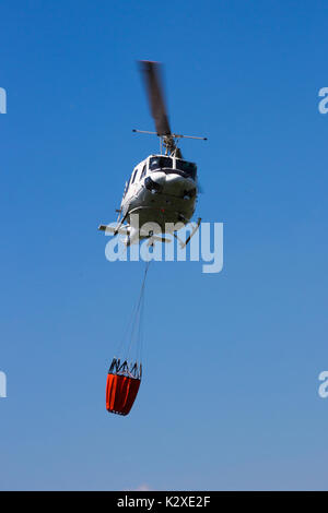 Hubschrauber mit einem Bambi Eimer mit Wasser gefüllt, einen Waldbrand zu bekämpfen. Stockfoto