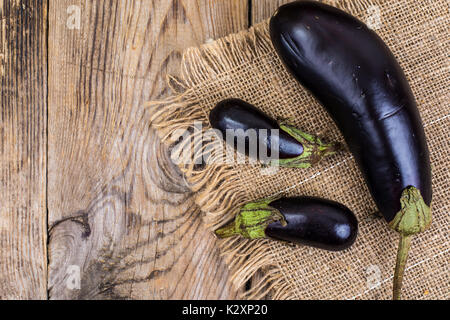 Ein großer und zwei kleine Aubergine auf Holz- Hintergrund. Studio Foto Stockfoto