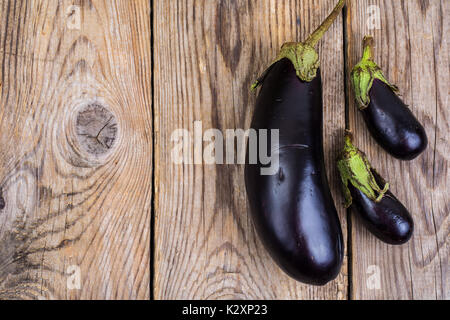 Ein großer und zwei kleine Aubergine auf Holz- Hintergrund. Studio Foto Stockfoto