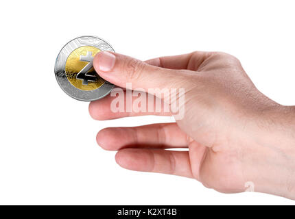 Eine männliche Hand mit einem physischen zcash cryptocurrency in Gold und Silber münze Form auf einem dunklen Studio Hintergrund Stockfoto