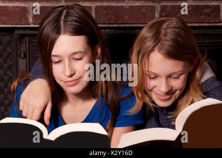 Zwei Schwestern lesen Bücher zusammen mit Arme um ihre Schultern. Stockfoto