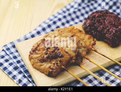 Thai Schweinebraten und schwarzen klebrigen Reis auf Holz Tisch Stockfoto