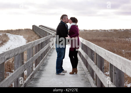 Erwartungsvollen Paare küssen auf Holzbrücke über Sanddünen. Stockfoto