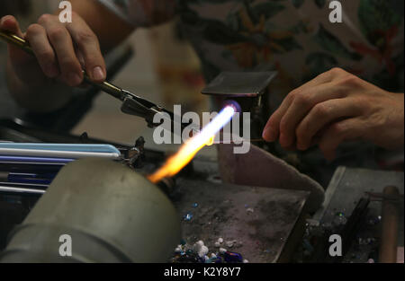 Glasmacher beim Schmelzen und formen Sie das Glas mit einem sehr hohen Temperatur Flamme in seiner handwerklichen Übung in Italien Stockfoto