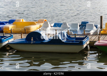 Bunte Tretboote an einen Holzsteg an einem See. Stockfoto