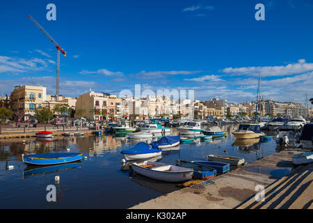MSIDA, MALTA - 19. OKTOBER 2016: Viele schöne Boote im kleinen Hafen mit Stadtbild auf dem Hintergrund Stockfoto