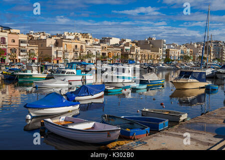 MSIDA, MALTA - 19. OKTOBER 2016: Viele schöne Boote im kleinen Hafen mit Stadtbild auf dem Hintergrund Stockfoto