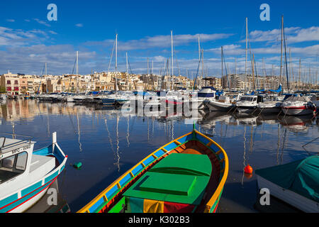MSIDA, MALTA - 19. OKTOBER 2016: Viele schöne Boote im kleinen Hafen mit Stadtbild auf dem Hintergrund Stockfoto
