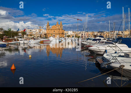 MSIDA, MALTA - 19. Oktober 2016: Die schöne Pfarrkirche in sonniger Tag mit Hafen im Vordergrund. Stockfoto
