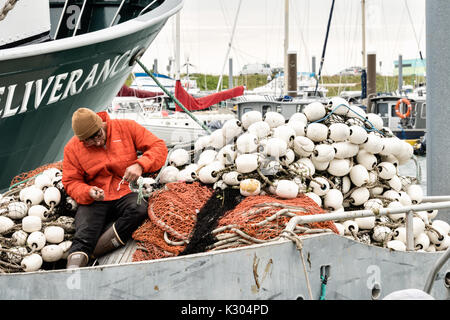 Ein Besatzungsmitglied des Hanta zu angeln Boot Reparaturen Netze in der Vorbereitung für Sie das Meer an der Stadt von Homer Port & Hafen Marina auf Kamishak Bay in Homer, Alaska zu. Stockfoto