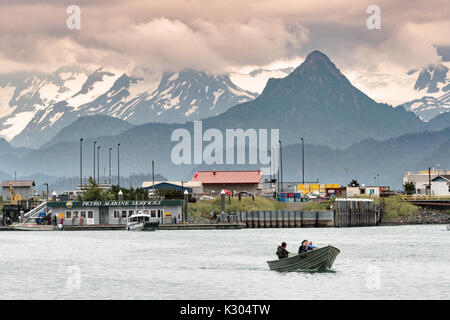 Ein kleines Fischerboot kehrt vom Fischfang in der Kamishak Bay an die Stadt Homer Port & Hafen Marina mit der Kenai Mountains hinter in Homer, Alaska. Stockfoto