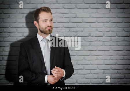 Schöne elegante Geschäftsmann in Anzug Kopie Raum, graue Mauer im Hintergrund Stockfoto