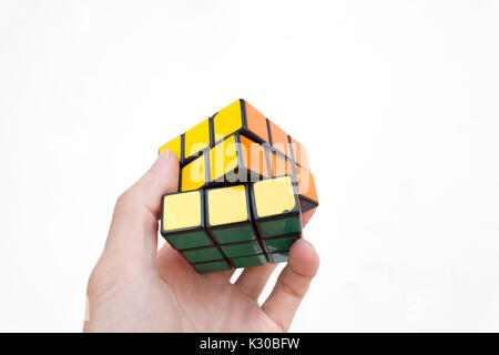 Magic Cube oder Rubik's Magic Cube, eine Hand zu lösen, gegen den weißen Hintergrund Stockfoto