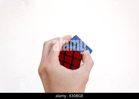 Magic Cube oder Rubik's Magic Cube, eine Hand zu lösen, gegen den weißen Hintergrund Stockfoto