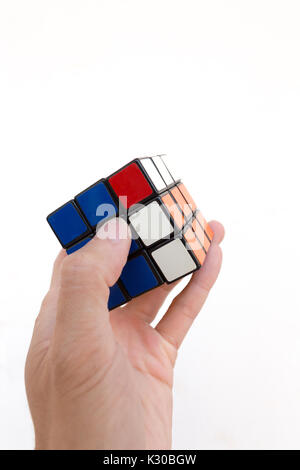 Magic Cube oder Rubik's Magic Cube, eine Hand zu lösen, gegen den weißen Hintergrund Stockfoto