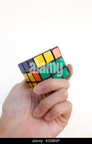 Magic Cube oder Rubik's Magic Cube, eine Hand zu lösen, gegen den weißen Hintergrund Stockfoto