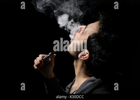 Junger Mann vaping eine E-Cig oder elektronische Zigarette mit einem Mod isoliert. Stockfoto