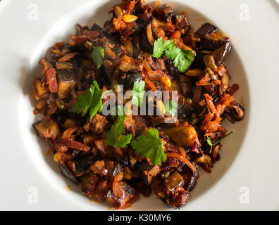 In der Nähe der Sizilianischen Teller, Caponata, mit Aubergine, Oliven, Kapern, Zwiebeln, Pinienkernen, Tomatenmark, auf einem weißen Teller serviert Stockfoto