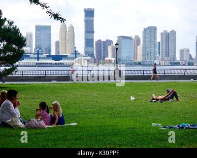 Battery Park, New York, NY, USA. Aktive Menschen unterschiedlichen Alters im Battery Park entspannen auf dem Hudson River mit Jersey City im Hintergrund. Stockfoto