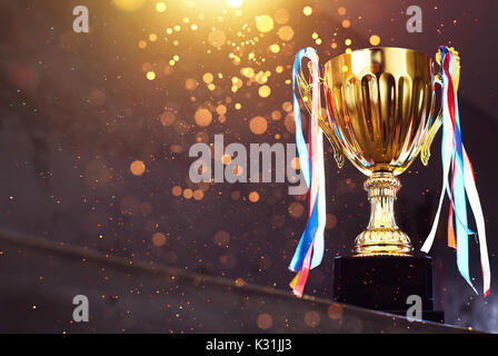 Low Key golden Trophy auf dem Blur grauer Hintergrund mit abstrakten glänzende Lichter. Stockfoto