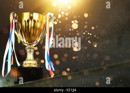 Low Key golden Trophy auf dem Blur grauer Hintergrund mit abstrakten glänzende Lichter. Stockfoto