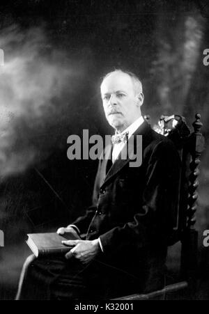 Sepia Porträt Foto, Taille, von Henry Clarke, Fellow und Professor der klassischen griechischen und lateinischen an der Johns Hopkins University, mit Buch in der Runde sitzt, trägt Anzug und Fliege, Baltimore, Maryland, 1905. Stockfoto