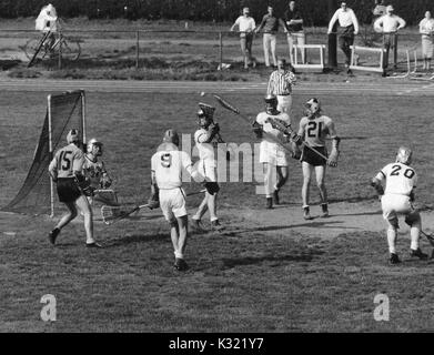 Graustufen Aktion Foto während einen Men's lacrosse Übereinstimmung zwischen der Johns Hopkins University und der United States Military Academy in West Point, als der Schiedsrichter bläst seine Pfeife zu Ende ein Speichern von einer Armee der Verteidigung Mitglied abgeholt, mit JHU Spieler Billy Morrill Nummer 15 und John jory Nummer 21 von Mitgliedern der gegnerischen Mannschaft, Baltimore, Maryland umgeben, 27. April 1957. Stockfoto