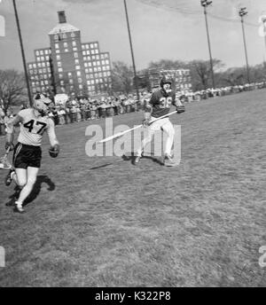 Während ein lacrosse Spiel, ein Loyola defenseman geht für Johns Hopkins Co - Kapitän und attackman Byron Forbush (keine, 1951. 47), auf dem Homewood Feld in Baltimore, Maryland. Stockfoto