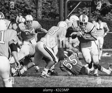 Ein Johns Hopkins University football player läuft mit dem Fußball-Vergangenheit Menschen angegangen, als Spieler der gegnerischen Mannschaft schließt in ihm an der Johns Hopkins University, Baltimore, Maryland, 1980 in Angriff zu nehmen. Stockfoto