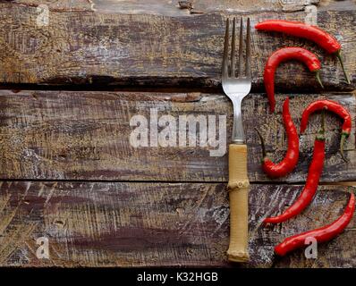 Red chili peppers auf einem Holztisch mit einer Gabel, Konzept, selektiver Fokus, Ansicht von oben Stockfoto