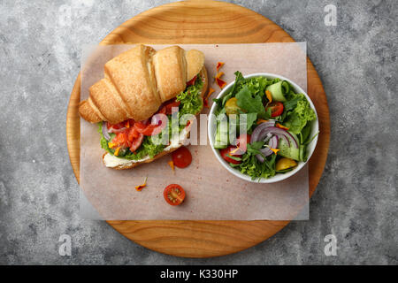 Croissant mit Lachs und Salat in der Schüssel, Essen flach Stockfoto