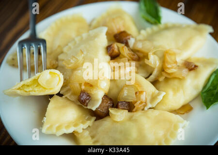 Gekochte Klöße mit Kartoffeln und Zwiebeln auf einer Platte Stockfoto