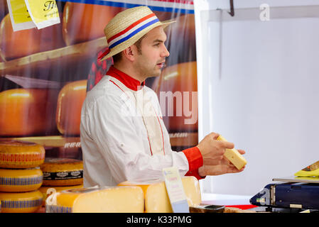 Kristiansand, Norwegen - 16. August 2017: Reisen Dokumentarfilm von Street Market. Niederländische Cheeseman Anbieter halten und zeigen ein Stück Käse. Stockfoto