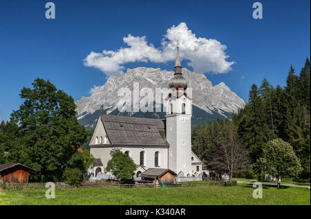 Typische Kirche alpinen Dorfes umgeben von Gipfeln und Wald Garmisch Partenkirchen Oberbayern Region Bayern Deutschland Europa Stockfoto