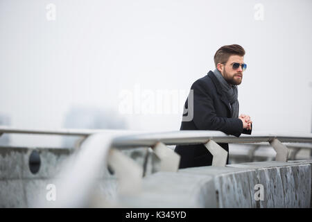 Ein Foto der Mann auf der Brücke stehen und vorausschauend denken über etwas. Stockfoto