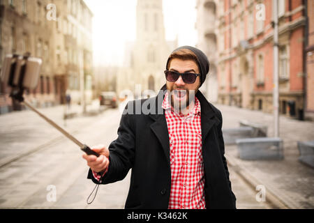 Ein Foto der jungen, trendigen Mann selbst ein Foto von seinem Handy. Er macht lustige Gesichter. Stockfoto