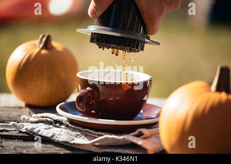 Mann filter Kaffee brühen Outdoor, im Herbst Kaffee Picknick, auf dem alten beschädigt Holztisch Hintergrund. Kaffee tropft in Bewegung in der Pro erfasst Stockfoto