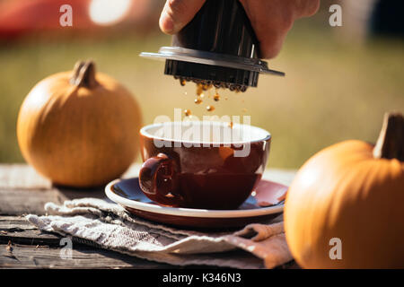 Mann filter Kaffee brühen Outdoor, im Herbst Kaffee Picknick, auf dem alten beschädigt Holztisch Hintergrund. Kaffee tropft in Bewegung in der Pro erfasst Stockfoto