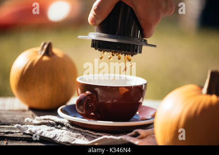 Mann filter Kaffee brühen Outdoor, im Herbst Kaffee Picknick, auf dem alten beschädigt Holztisch Hintergrund. Kaffee tropft in Bewegung in der Pro erfasst Stockfoto