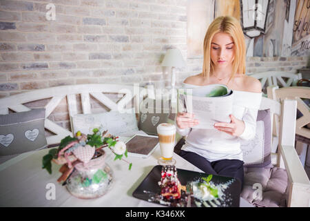 Ein Foto der jungen, schönen Frau liest eine Zeitschrift im Café. Stockfoto