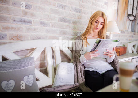 Ein Foto der jungen, schönen Frau liest eine Zeitschrift im Café. Stockfoto