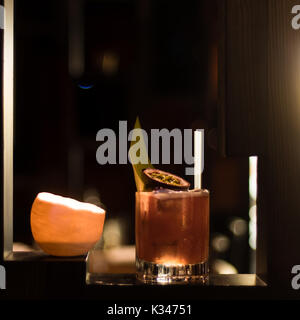 Frucht Cocktail Licht der Kerze und mit Bild und Blatt geschmückt. Alkoholische Getränk in old fashioned Glas in bar Stockfoto