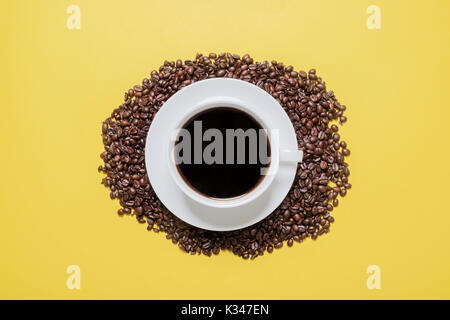 Schwarzen Kaffee in der Tasse mit Bohnen auf gelben Hintergrund Stockfoto